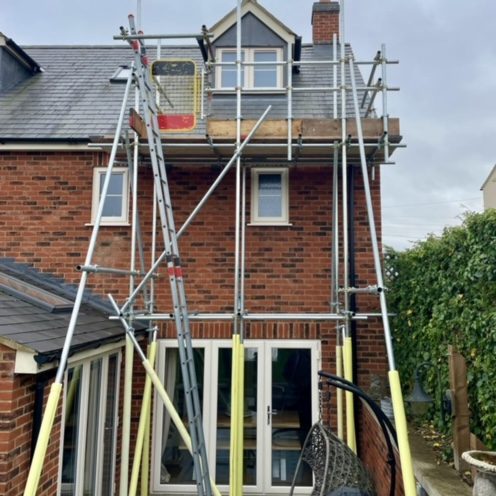 Access tower scaffolding for roof repairs Scaffolding set up outside a brick house for repair work on the roof.