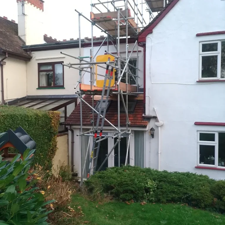 Chimney access scaffolding Scaffolding set up on a house, with a nearby garden and hedges visible.